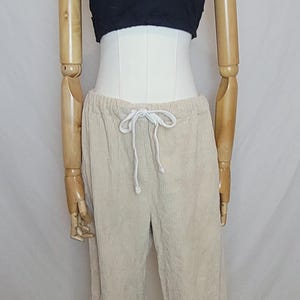 May include: A black tube top and beige corduroy pants with a drawstring waist are displayed on a mannequin. A silver chain necklace is worn with the top. The pants have a relaxed fit.
