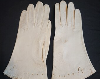 May include: A pair of off-white leather gloves with decorative stitching around the wrist.