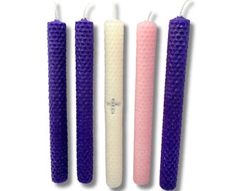 May include: Set of five Advent candles, four purple and one pink, with a white candle in the center. The white candle has a small silver cross on it.