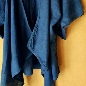 Puede incluir: Una blusa azul oscuro de tejido suave y texturado. La blusa tiene un escote en V y mangas cortas.