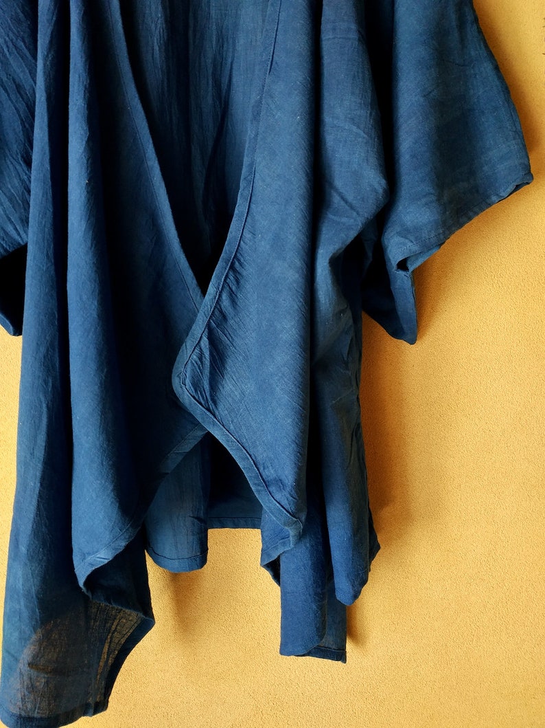 Puede incluir: Una blusa azul oscuro de tejido suave y texturado. La blusa tiene un escote en V y mangas cortas.