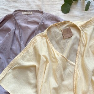 Puede incluir: Dos blusas de algod&oacute;n, una de color morado claro y otra de color amarillo p&aacute;lido. Ambas blusas tienen cuello en V y mangas cortas. Las blusas tienen una etiqueta que dice "Maka Handmade".