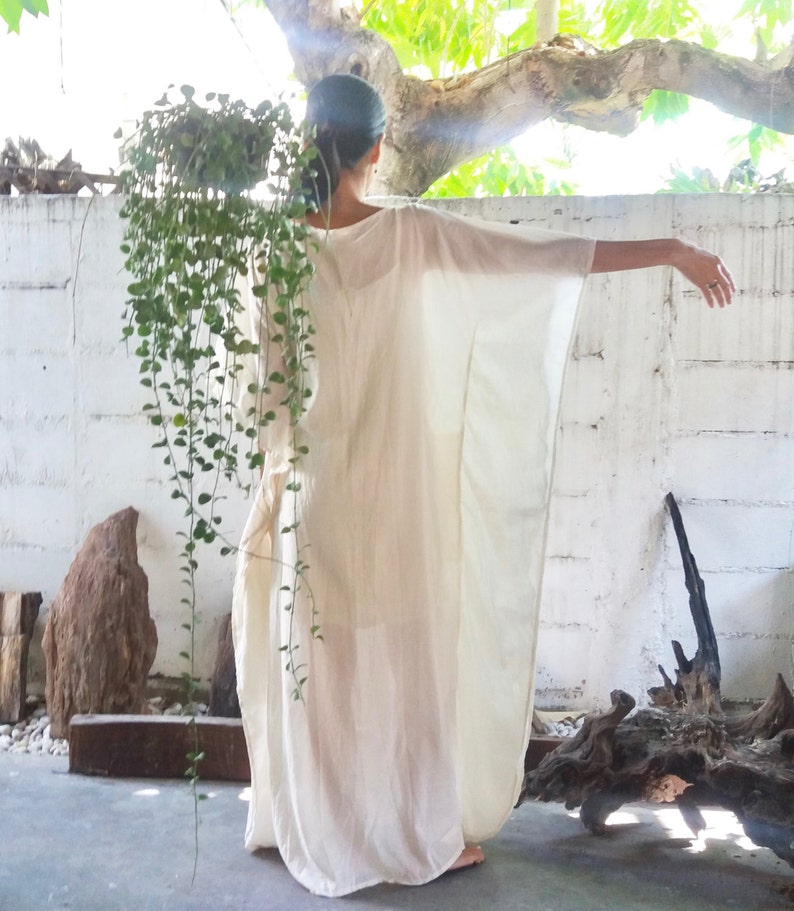 Puede incluir: Un vestido blanco de kaft&aacute;n fluido con un corte holgado y relajado. El vestido est&aacute; hecho de una tela ligera y tiene un dise&ntilde;o simple y elegante.