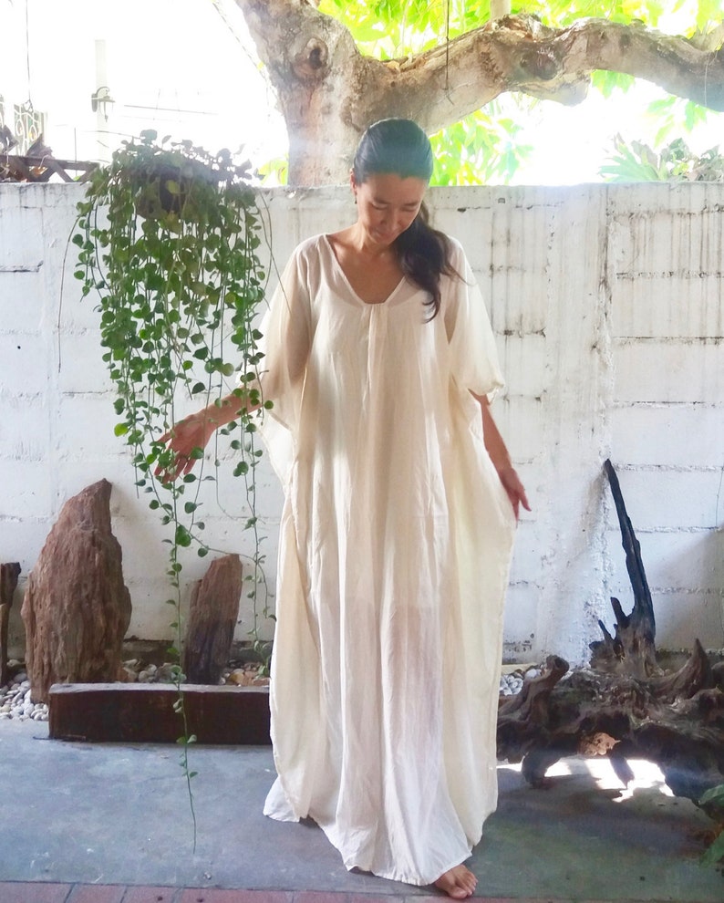 Puede incluir: Un vestido blanco de kaft&aacute;n fluido con escote redondo y mangas cortas. El vestido est&aacute; hecho de una tela ligera y tiene un corte holgado.