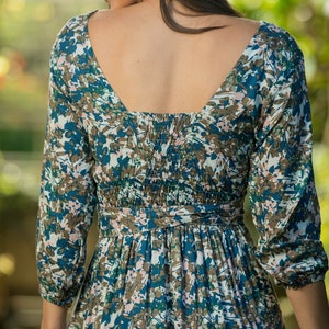 May include: A blue and brown floral print dress with a low back and a gathered waist. The dress has long sleeves and a tiered skirt.