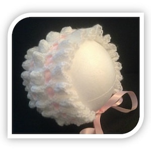 May include: White crocheted baby bonnet with a pink satin ribbon and a pink crocheted trim.