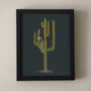 May include: A framed print of a stylized illustration of a green cactus with a pink flower on a dark blue background. The print includes the text "BISON PAPER CO."