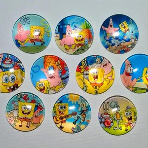 May include: Nine colorful round buttons featuring cartoon characters from the animated television series Spongebob Squarepants. The buttons feature various scenes with Spongebob, Patrick, Squidward, and other characters.