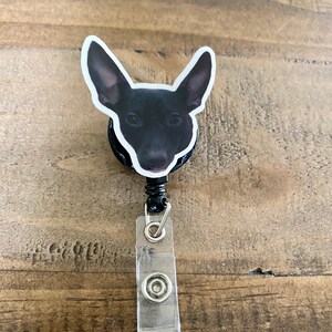 May include: Black and white dog head badge reel with a clear plastic badge holder.