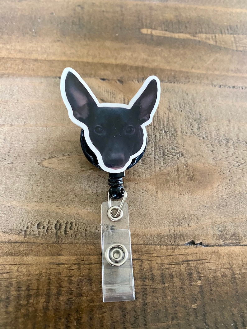 May include: Black and white dog head badge reel with a clear plastic badge holder.