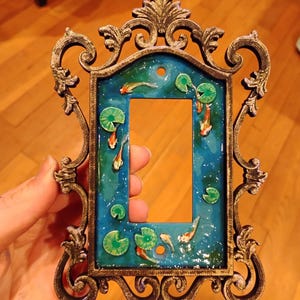 May include: A set of three ceramic mugs with a speckled, matte finish. The mugs are in shades of cream, light gray, and dark gray. Each mug has a simple, minimalist design and a rounded handle.