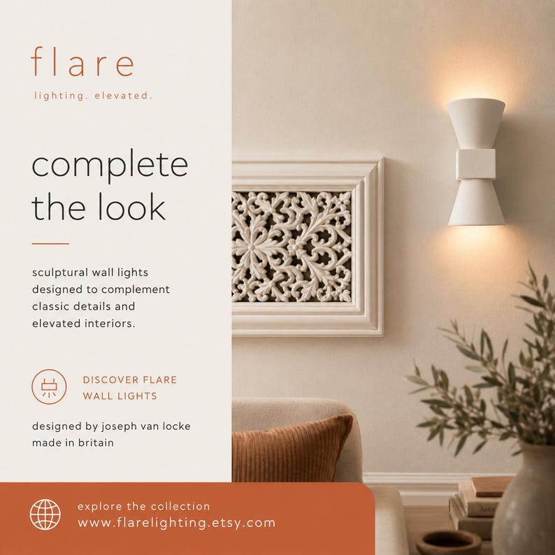 May include: White sculptural wall light with a double cone design, illuminating a warm glow. The image also features a decorative white framed wall art and text that reads "complete the look".