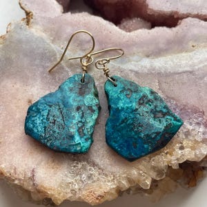 May include: A pair of turquoise green gemstone earrings with gold wire wrapped ear wires.