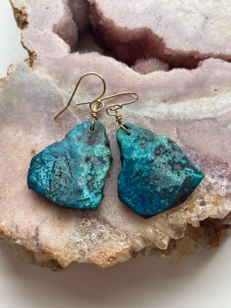May include: A pair of turquoise green gemstone earrings with gold wire wrapped ear wires.