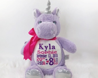 May include: Purple unicorn plush toy with a pink bow and silver hooves. The toy is personalized with the name "Kyla Sophie", the date "September 12, 2018", the time "12:07 AM", the weight "8 lbs", and the length "20 inches".