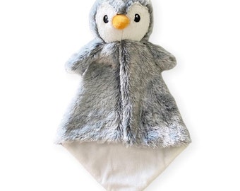 May include: A gray and white penguin plush security blanket with a soft, fuzzy texture. The penguin has black eyes, an orange beak, and a white belly.