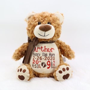May include: A brown teddy bear with a brown ribbon around its neck. The bear is embroidered with the name "Arthur" and the text "Henry Van Horn 2-26-2020 20" 6:57PM 9lb 2oz".