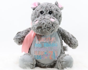 Könnte beinhalten: Graues Plüsch-Nilpferd-Stofftier mit rosa Ohren und einem rosa Band. Das Nilpferd ist mit dem Namen "Hazelyn Ann Rhodes", dem Datum "1. September 2021" und den Maßen "19,69" Zoll, 7 Pfund, 10 Unzen bestickt.