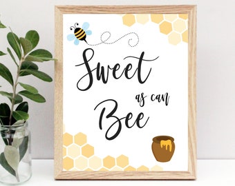May include: A white sign with a wooden frame, featuring a cartoon bee and honeycomb pattern. The sign reads "Sweet as can Bee".