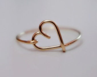 May include: A gold heart-shaped ring. The ring is made of thin wire and has a simple design.