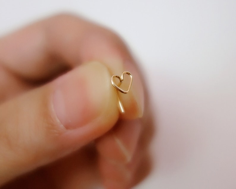 May include: A gold heart-shaped earring with a delicate wire design.