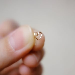 May include: A gold heart-shaped earring with a delicate wire design.