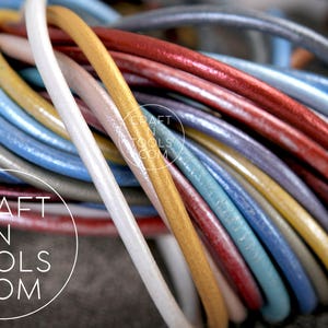 May include: A close-up of a variety of leather cords in different colors, including gold, red, blue, and white. The cords are arranged in a circular pattern, creating a colorful and textured design. The text "CRAFT N TOOLS .COM" is visible in the center of the image.