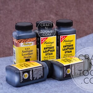 May include: Four bottles of Fiebing's Antique Leather Stain in black, dark brown, and mahogany. The bottles are labeled with the Fiebing's logo and product information. The bottles are on a gray fabric surface.