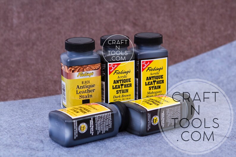 May include: Four bottles of Fiebing's Antique Leather Stain in black, dark brown, and mahogany. The bottles are labeled with the Fiebing's logo and product information. The bottles are on a gray fabric surface.