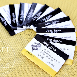 May include: A pack of 25 felting needles, labelled "John James" with a dragon logo. The needles are size 002 and are 3.91 inches long. The packaging is yellow and black with the text "Glovers Aiguilles pour pelletier Kurschnernadeln L3910 Size 002" and "25 Needles".