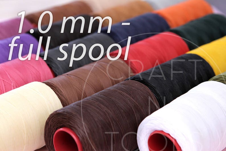 Puede incluir: Primer plano de carretes de hilo encerado, cada uno de un color diferente. Los carretes est&aacute;n dispuestos en una fila, con el texto "1.0 mm - full spool" visible en la parte superior de la imagen.