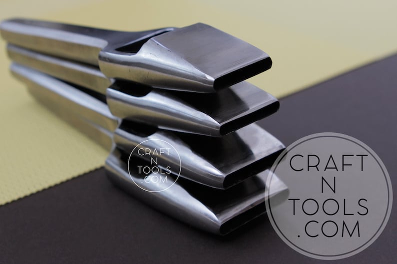 May include: A stack of four metal leather working tools with rectangular cutting heads. The tools are silver and reflect light, with a dark background. The tools are arranged in a diagonal stack. The logo "CRAFT N TOOLS .COM" is in the lower right corner.
