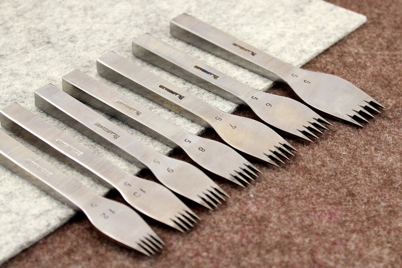 May include: Set of eight silver leather stitching tools with different sized prongs. The tools are labeled with the number of prongs, ranging from 1 to 8.