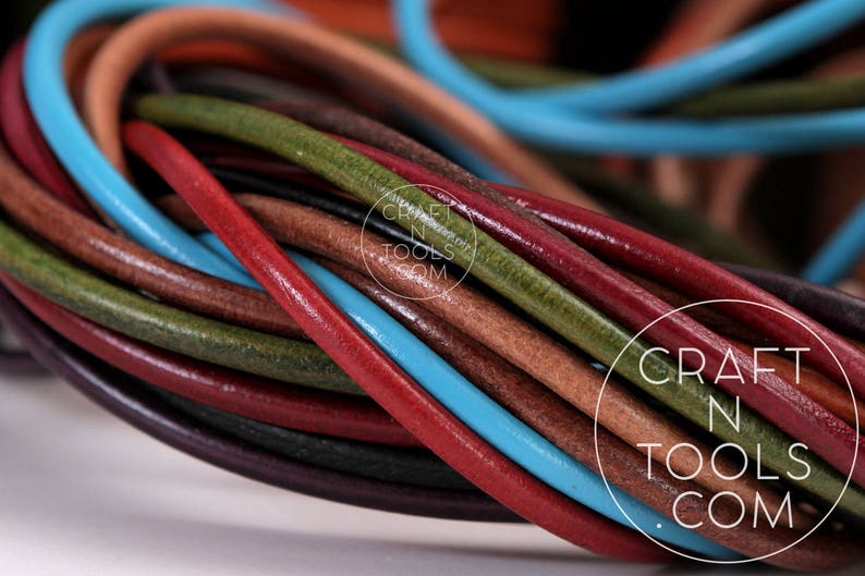 May include: A close-up of a bundle of colorful leather cords. The cords are in various shades of brown, red, green, and blue. The cords are arranged in a circular pattern, with the ends of the cords overlapping. The cords are all of the same thickness and are smooth to the touch. The cords are perfect for crafting projects, such as jewelry making, leatherworking, and macrame.