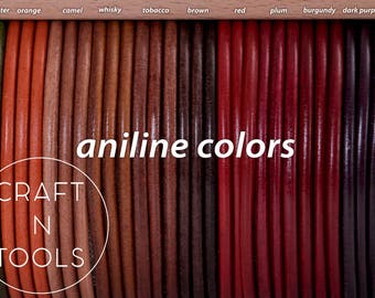 May include: A close-up of a variety of leather cords in different colors, including green hunter, orange, camel, whisky, tobacco, brown, red, plum, burgundy, dark purple, and black. The cords are arranged in a row and labeled with their corresponding colors. The text "aniline colors" is written in white letters on a black background. The text "CRAFT N TOOLS" is written in white letters on a circle with a black outline.