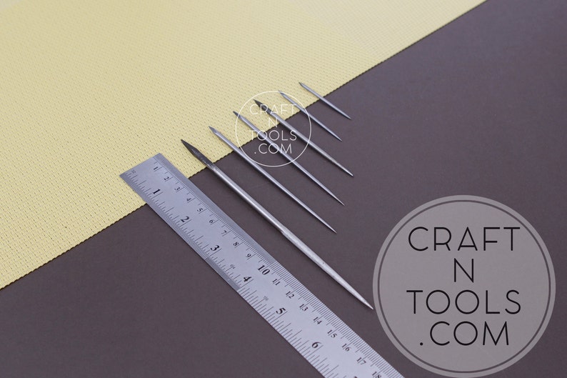 May include: Six silver metal tools of varying lengths, laid out on a brown surface next to a ruler marked in inches. The tools are arranged from shortest to longest. The longest tool is 6 inches long. The tools are all pointed at one end. The background is a yellow surface. The text "CRAFT N TOOLS .COM" is visible in a circle on the brown surface.