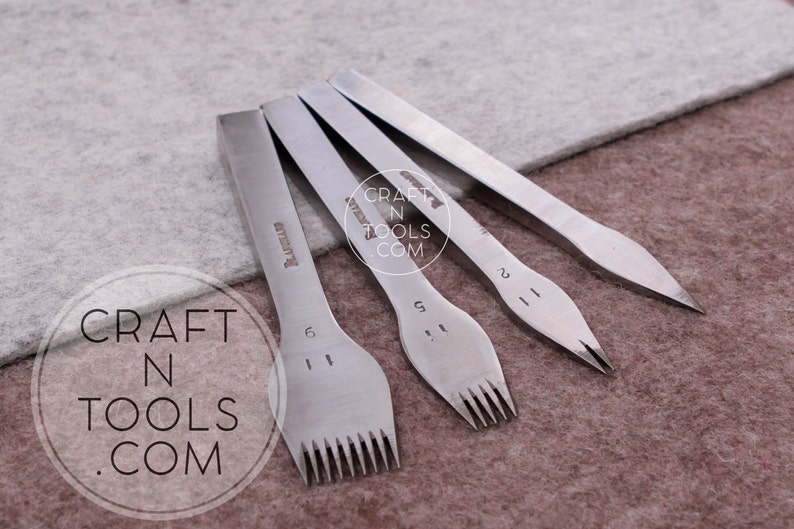 May include: Four silver leather stitching tools with different sized prongs. The tools are labeled with the number of prongs: 6, 5, 2, and 1. The tools are on a brown surface.