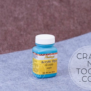May include: A blue bottle of Fabtags Acrylic Dye for Leather in the color Turquoise. The bottle is labeled with the brand name, product name, color, and net weight of 2 oz (59 ml).