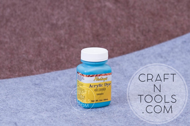 May include: A blue bottle of Fabtags Acrylic Dye for Leather in the color Turquoise. The bottle is labeled with the brand name, product name, color, and net weight of 2 oz (59 ml).