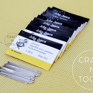 May include: A pack of 25 John James Glovers needles, size 002, for pelletier and kurschnernadeln. The needles are silver and come in a yellow and black package with the text "John James Glovers Aiguilles pour pelletier Kurschnernadeln L3910 Size 002" printed on it.