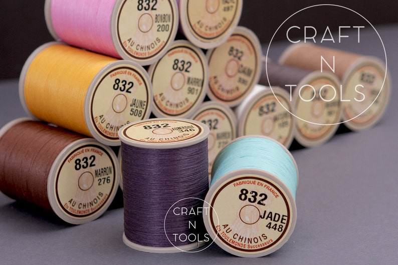 May include: A close-up of a variety of spools of thread in different colors, including pink, yellow, brown, purple, and blue. The spools are labeled with the brand name "Au Chinois" and the color name and number. The spools are arranged in a pyramid shape. The text "CRAFT N TOOLS" is visible in the background.
