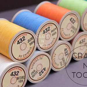 May include: Close-up of spools of thread in various colors, including yellow, blue, orange, green, and white. Each spool has a label with the number 432 and a description in French. The label also includes the text "CRAFT N TOOLS".