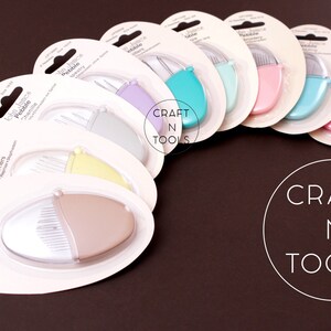 K&ouml;nnte beinhalten: Ein Set mit zehn John James Pebble Quilting-Werkzeugen in verschiedenen Farben, darunter hellblau, rosa und gelb. Die Werkzeuge sind in einzelnen durchsichtigen Plastikbeh&auml;ltern mit wei&szlig;em Hintergrund und schwarzem Text verpackt.