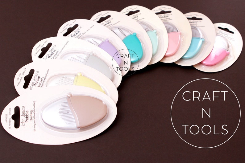 K&ouml;nnte beinhalten: Ein Set mit zehn John James Pebble Quilting-Werkzeugen in verschiedenen Farben, darunter hellblau, rosa und gelb. Die Werkzeuge sind in einzelnen durchsichtigen Plastikbeh&auml;ltern mit wei&szlig;em Hintergrund und schwarzem Text verpackt.