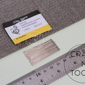 May include: A pack of 25 silver glovers needles, size 002, with a yellow and white label that reads "John James Glovers Aiguilles pour pelletier Kurschnernadein L3910 Size 002 25 Needles".