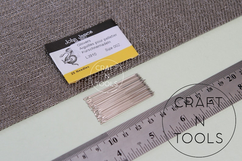 May include: A pack of 25 silver glovers needles, size 002, with a yellow and white label that reads "John James Glovers Aiguilles pour pelletier Kurschnernadein L3910 Size 002 25 Needles".
