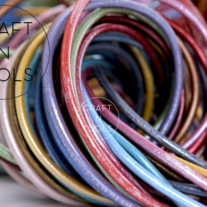 May include: A close-up of a bundle of colorful leather cords. The cords are arranged in a circular pattern, with the ends of the cords overlapping. The cords are a variety of colors, including red, blue, green, yellow, and purple. The cords are all smooth and shiny, and they appear to be made of high-quality leather. The text "CRAFT N TOOLS" is visible in the background.