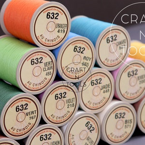 May include: A close-up of a stack of spools of thread, each spool is labeled with a number, a color name, and the text "Au Chinois". The spools are arranged in a circular pattern, with the top spool in the center.