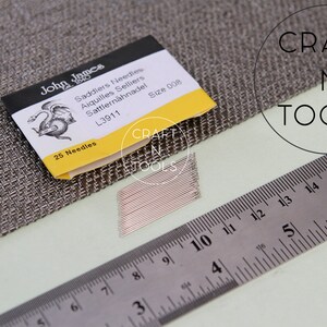May include: A pack of 25 John James Saddlers Needles, size 008, with a dragon logo and the text "L3911" on the front. The needles are laid out next to a ruler, measuring 6 inches.