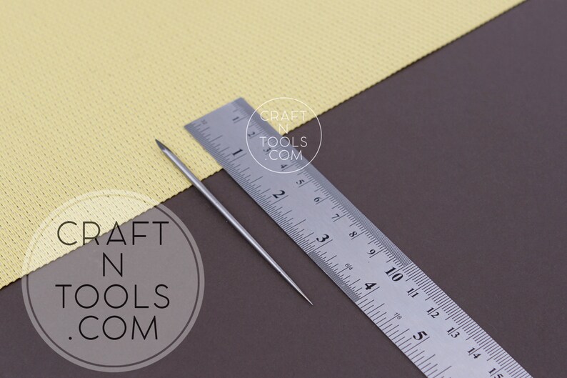 May include: A silver metal needle tool with a pointed tip, measuring approximately 4 inches in length, is placed on a brown surface next to a silver ruler. The ruler is marked with inches and fractions of an inch. The text "CRAFT N TOOLS .COM" is visible in the lower left corner of the image.